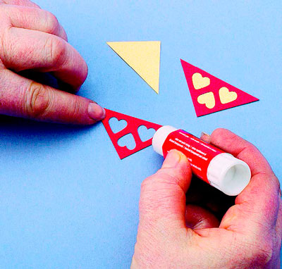 Акуратно приклейте до зворотної сторони кожного червоного трикутника трикутник із золотої паперу